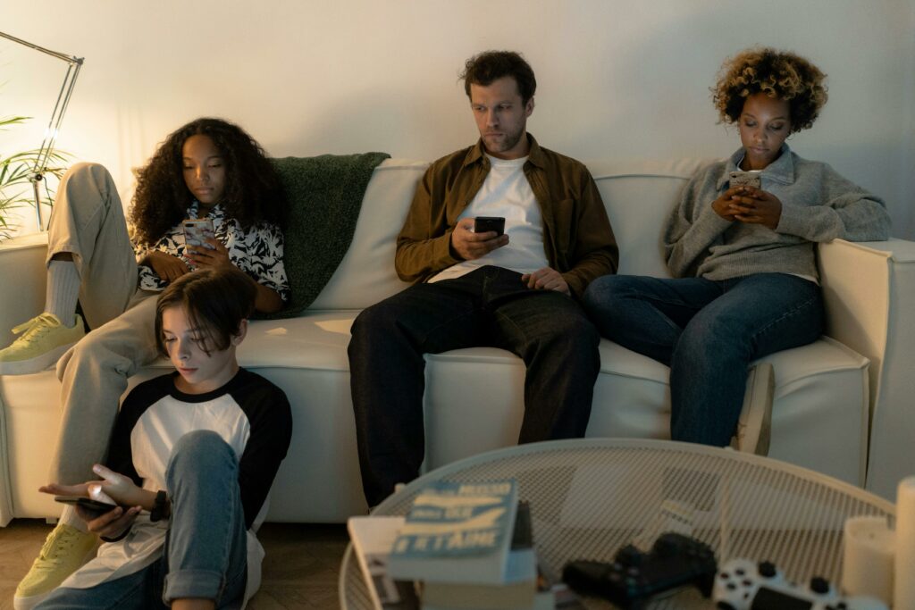 A Family Sitting on Sofa Holding CellphoneS