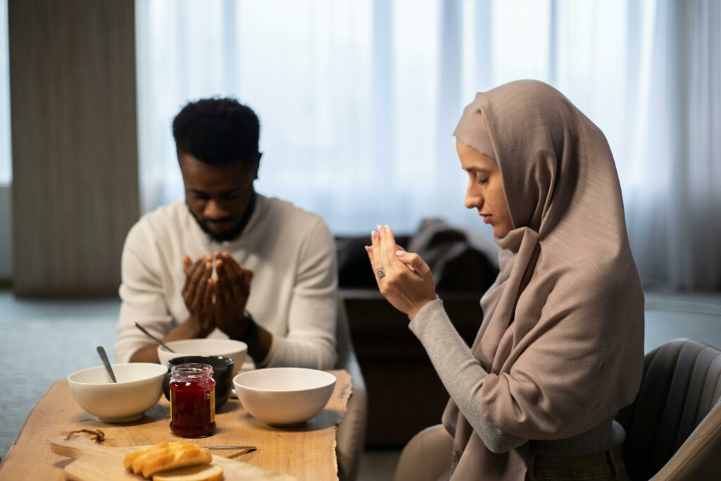 Multiethnic couple praying at table before eating