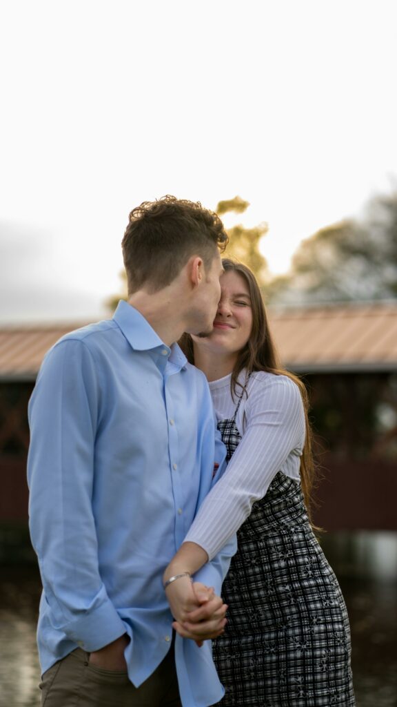 Cheerful couple smiling and kissing while holding hands