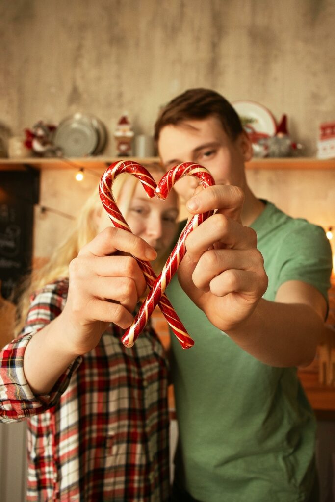 A Couple Holding Red Candy Canes Making a Heart Shape