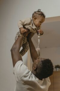 A Man in White Shirt Lifting a Baby
